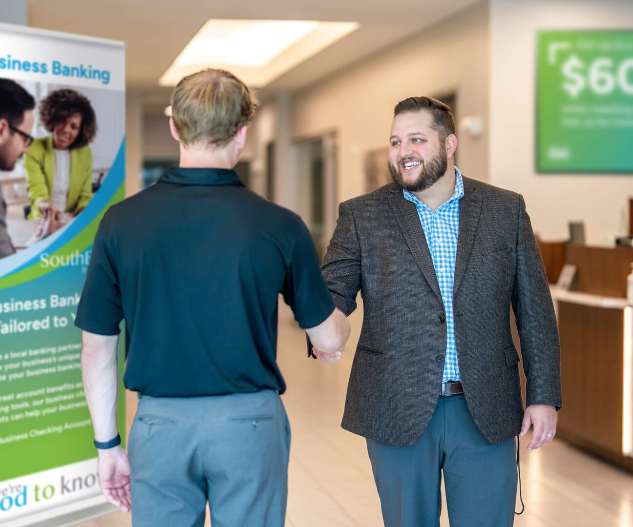 Two men shaking hands in a room with banners.