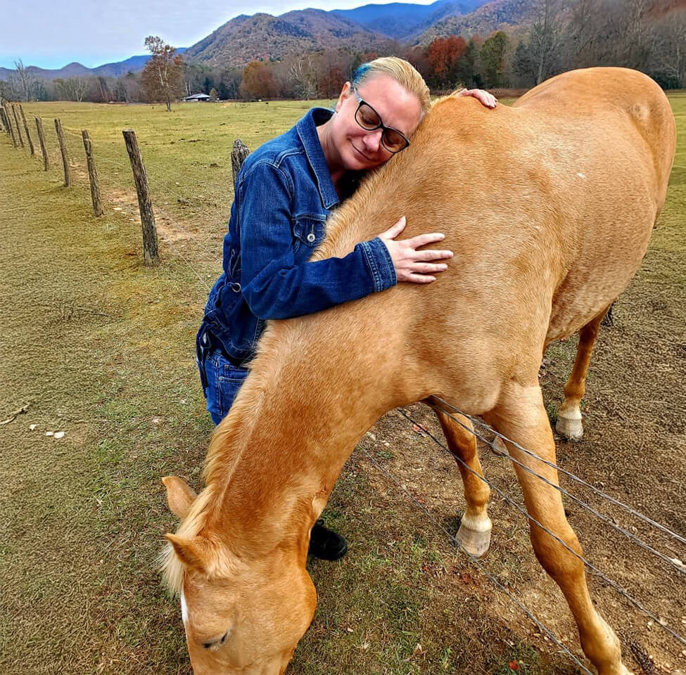 Woman hugging a palomino horse.